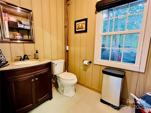 bathroom with toilet, vanity, and concrete flooring