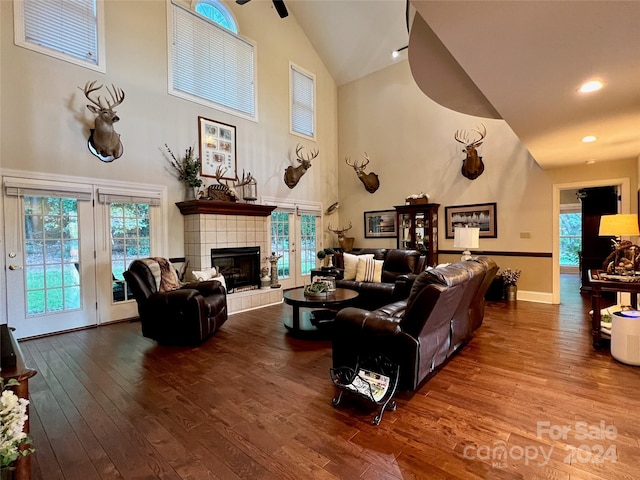 living room featuring ceiling fan, hardwood / wood-style flooring, high vaulted ceiling, and a tiled fireplace