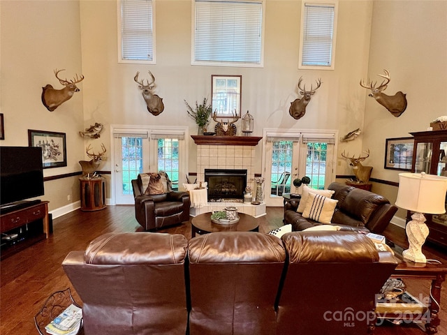 living room with a healthy amount of sunlight, a tiled fireplace, french doors, and dark hardwood / wood-style flooring