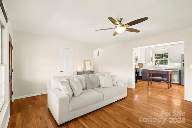 living room featuring sink, light wood-type flooring, and ceiling fan