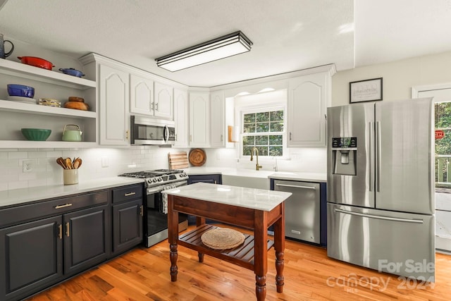 kitchen with white cabinetry, light wood-type flooring, appliances with stainless steel finishes, a textured ceiling, and tasteful backsplash