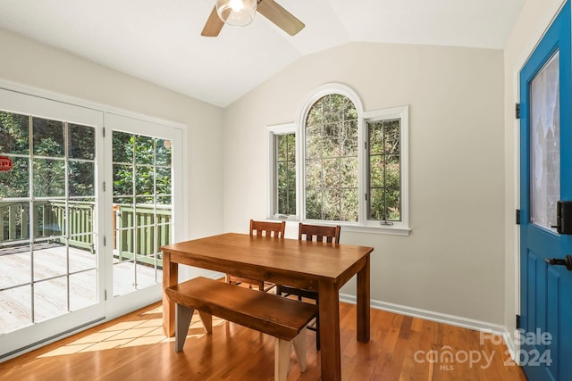 dining space with wood-type flooring, plenty of natural light, and vaulted ceiling