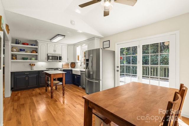 kitchen featuring appliances with stainless steel finishes, lofted ceiling, white cabinets, blue cabinetry, and light hardwood / wood-style flooring