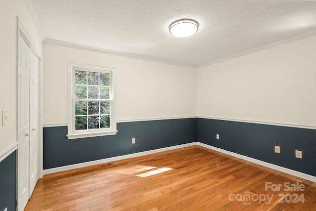 spare room featuring ornamental molding, a textured ceiling, and wood-type flooring