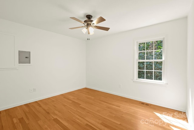 unfurnished room with light hardwood / wood-style floors, electric panel, and ceiling fan