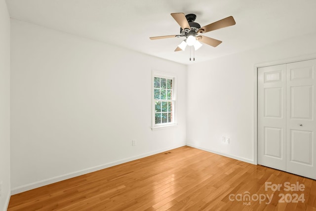 unfurnished bedroom featuring hardwood / wood-style floors, a closet, and ceiling fan