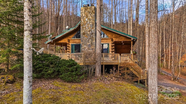 back of house with a wooden deck, a wooded view, a chimney, and stairway