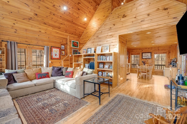 living area with wooden walls, wood ceiling, wood finished floors, and high vaulted ceiling