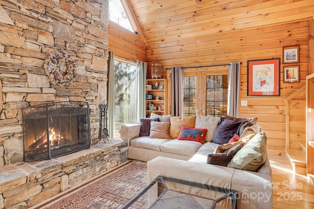 living room with wood finished floors, a fireplace, wood walls, and high vaulted ceiling