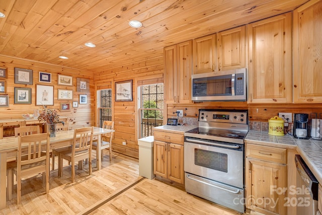 kitchen with light brown cabinets, light wood-style flooring, tile counters, wood ceiling, and appliances with stainless steel finishes