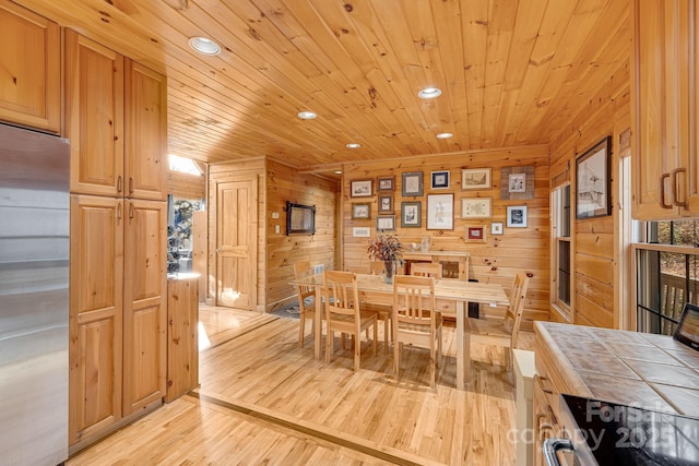 dining space with recessed lighting, wooden walls, wood ceiling, and light wood-style flooring