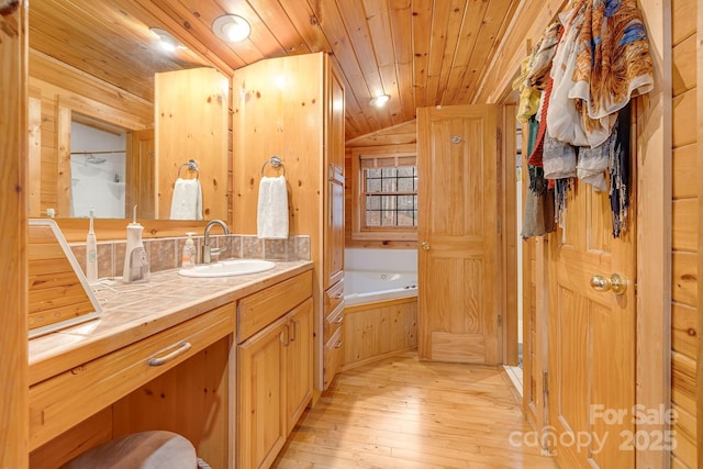 bathroom featuring hardwood / wood-style flooring, lofted ceiling, wood ceiling, a bath, and vanity
