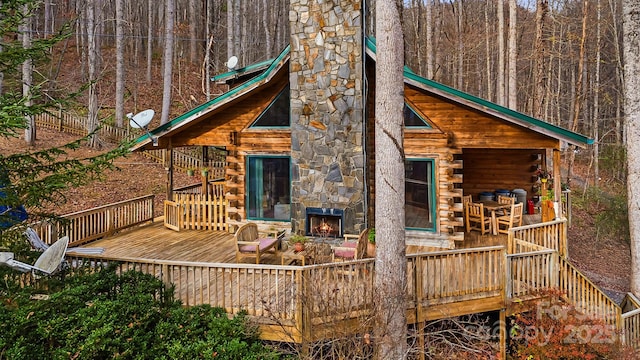 back of house featuring stairway, a deck, log exterior, and a chimney