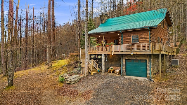 view of front of home featuring stairway, log siding, central AC, a chimney, and metal roof