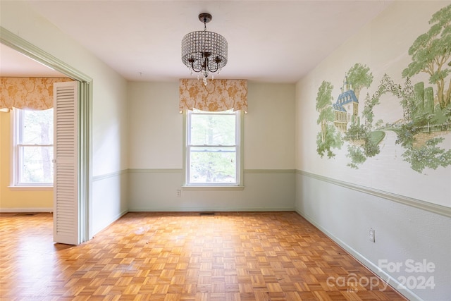 unfurnished room with light parquet flooring and a chandelier