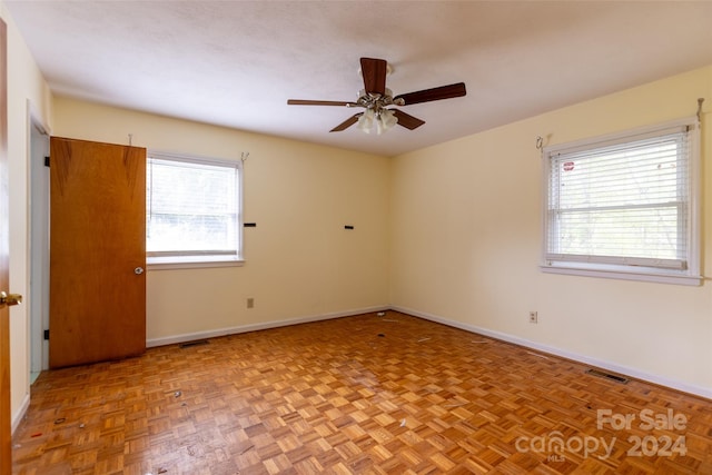 empty room with ceiling fan and light parquet flooring