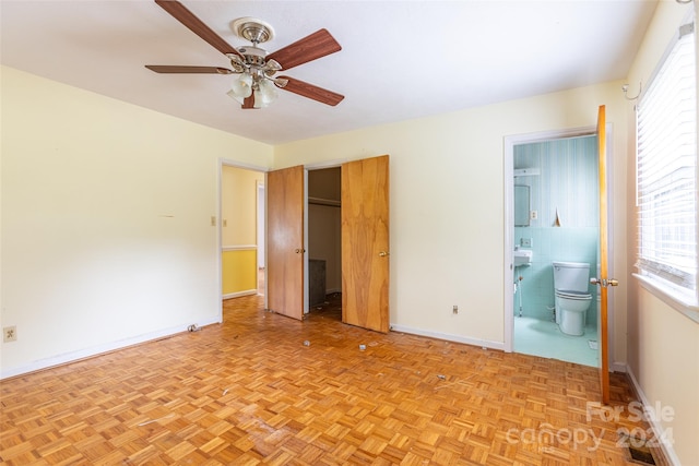 unfurnished bedroom featuring ceiling fan, light parquet flooring, and ensuite bath