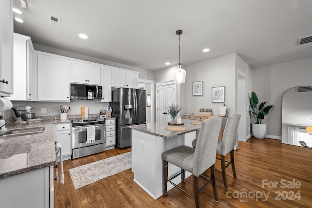 kitchen featuring dark wood-type flooring, white cabinets, appliances with stainless steel finishes, and a center island