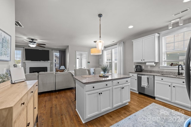 kitchen featuring a kitchen island, stainless steel dishwasher, white cabinets, dark wood-type flooring, and pendant lighting