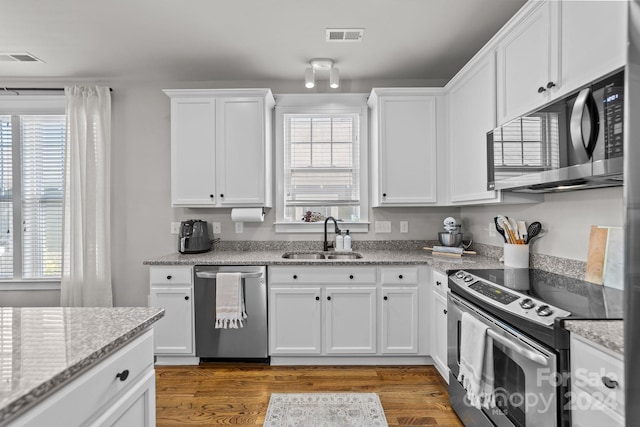 kitchen with a healthy amount of sunlight, sink, stainless steel appliances, and white cabinets