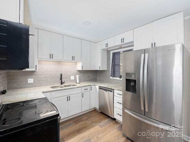 kitchen with sink, stainless steel appliances, light stone counters, white cabinets, and light wood-type flooring