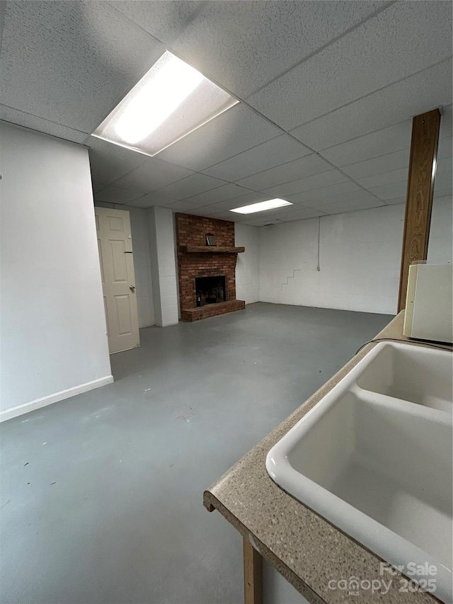 basement featuring a paneled ceiling, a fireplace, and sink