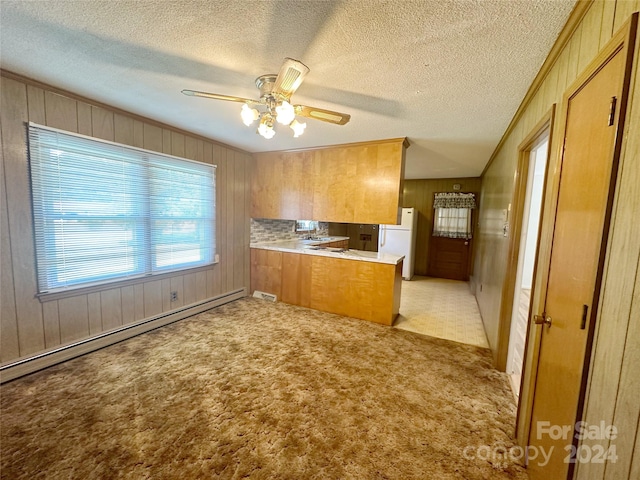 kitchen with light colored carpet, a textured ceiling, white refrigerator, and a baseboard heating unit