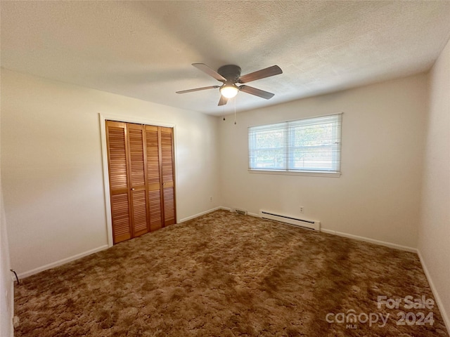 unfurnished bedroom featuring a closet, a textured ceiling, carpet floors, baseboard heating, and ceiling fan