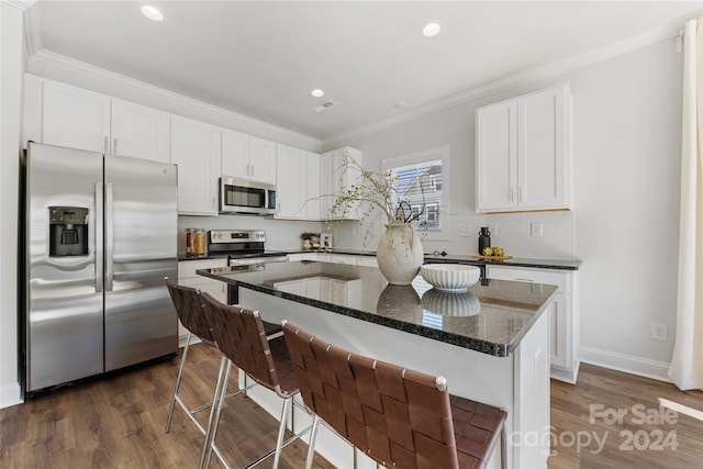 kitchen featuring white cabinets, a kitchen island, appliances with stainless steel finishes, dark stone countertops, and dark hardwood / wood-style floors