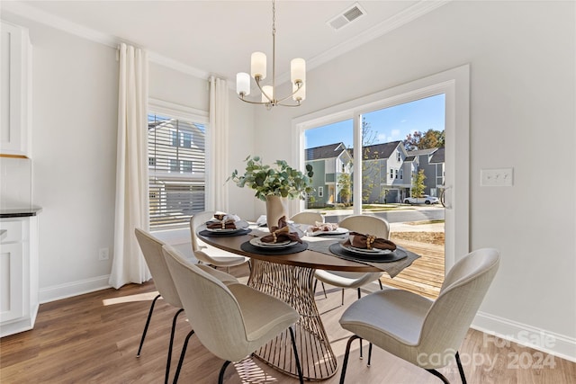 dining room with ornamental molding, a chandelier, and light hardwood / wood-style floors