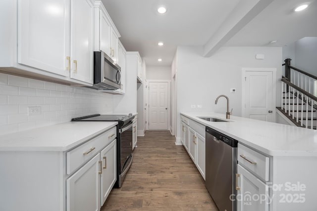 kitchen with appliances with stainless steel finishes, sink, white cabinets, dark hardwood / wood-style flooring, and decorative backsplash