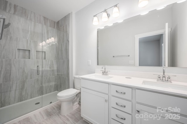 bathroom featuring a shower with door, vanity, and toilet