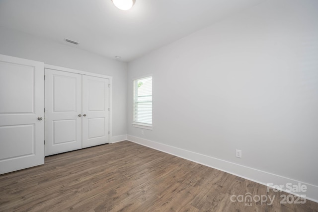 unfurnished bedroom featuring dark wood-type flooring and a closet