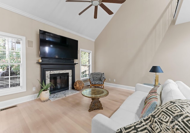 living room with high vaulted ceiling, a wealth of natural light, a high end fireplace, and light hardwood / wood-style flooring