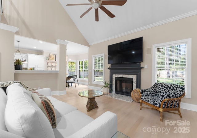 living room featuring a high end fireplace, light hardwood / wood-style flooring, high vaulted ceiling, and ceiling fan