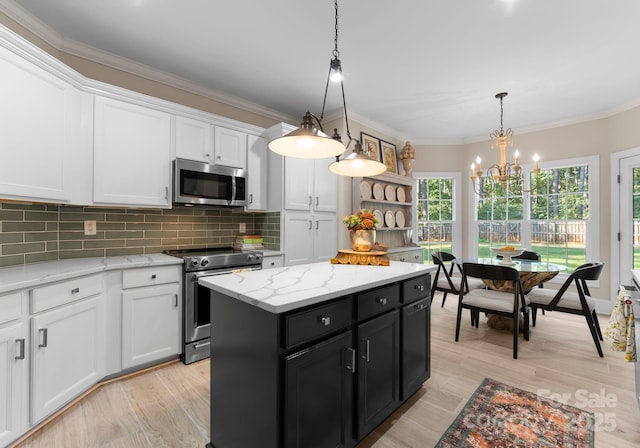 kitchen featuring a center island, stainless steel appliances, decorative light fixtures, decorative backsplash, and white cabinets