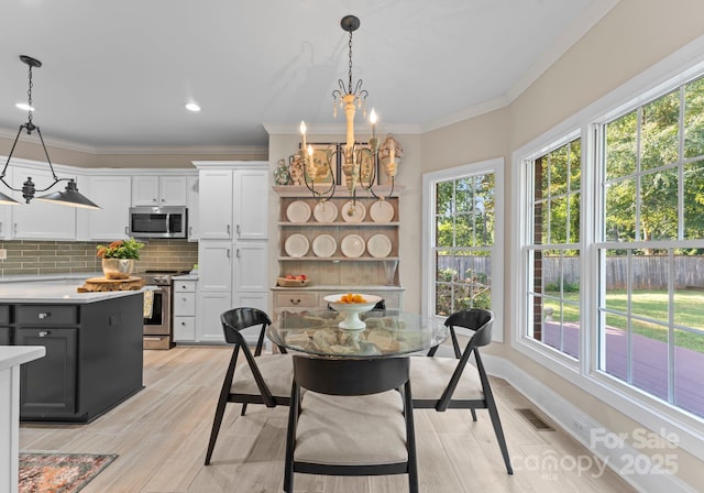 dining area featuring crown molding, light hardwood / wood-style flooring, and an inviting chandelier