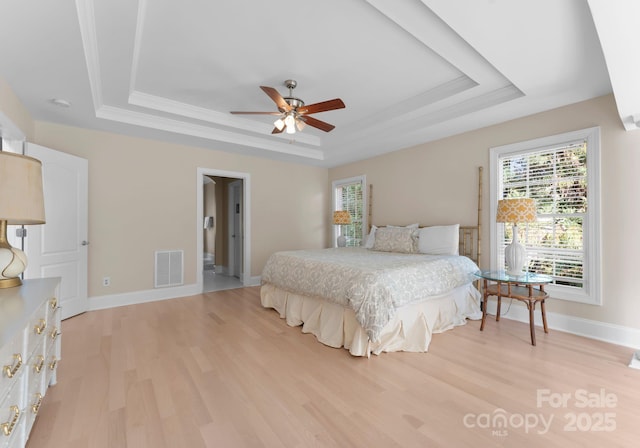 bedroom featuring light hardwood / wood-style floors, a raised ceiling, ceiling fan, and ornamental molding