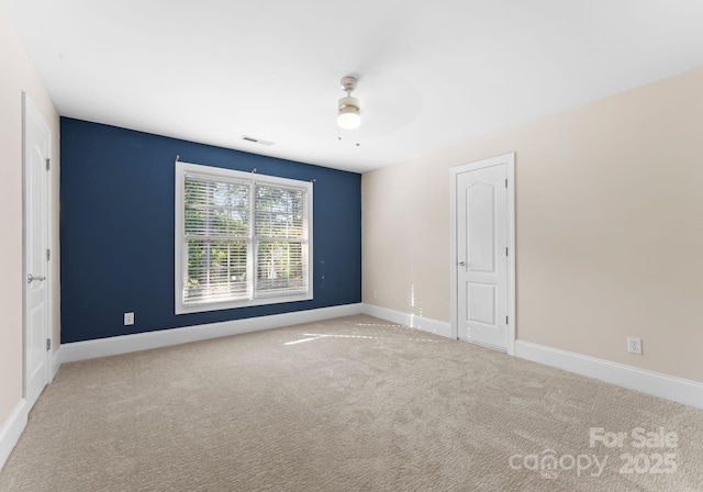 carpeted spare room featuring ceiling fan