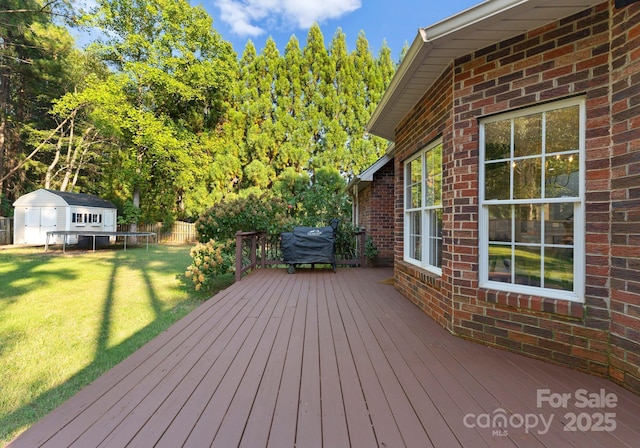 deck featuring a grill, a yard, and a storage unit