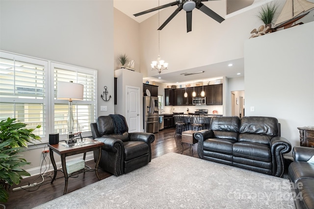 living room featuring dark wood-type flooring, ceiling fan with notable chandelier, and high vaulted ceiling