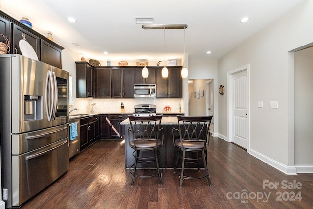 kitchen with pendant lighting, a kitchen island, dark hardwood / wood-style flooring, sink, and stainless steel appliances