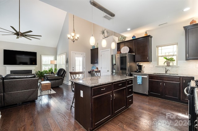 kitchen featuring appliances with stainless steel finishes, a kitchen island, a wealth of natural light, and decorative light fixtures