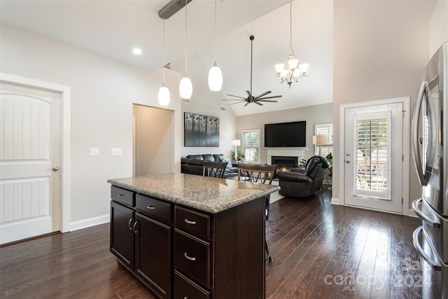 kitchen featuring a center island, stainless steel fridge, dark wood-type flooring, ceiling fan with notable chandelier, and pendant lighting