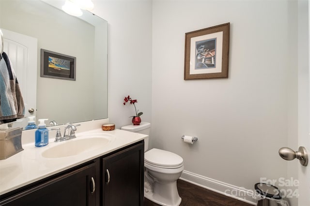 bathroom with wood-type flooring, vanity, and toilet