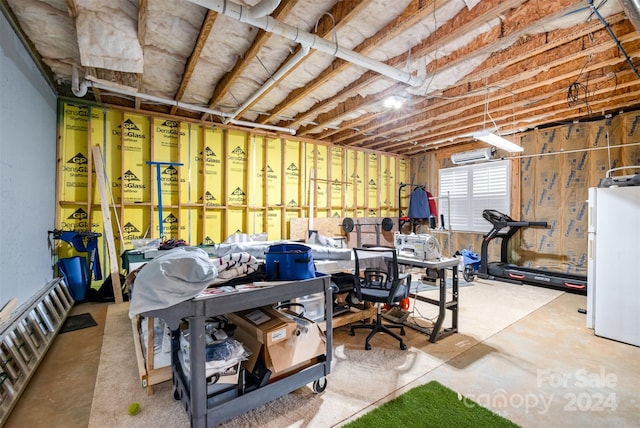 basement with white refrigerator and a wall mounted air conditioner