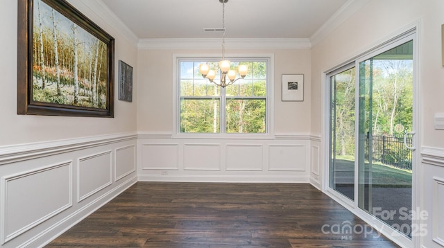 unfurnished dining area with dark hardwood / wood-style floors, crown molding, and an inviting chandelier