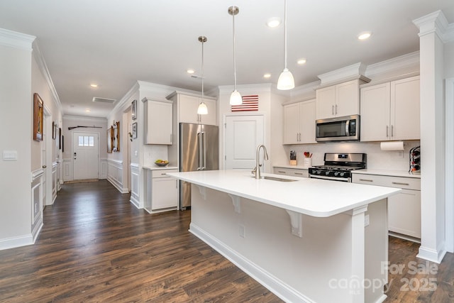 kitchen with pendant lighting, sink, an island with sink, appliances with stainless steel finishes, and dark hardwood / wood-style flooring