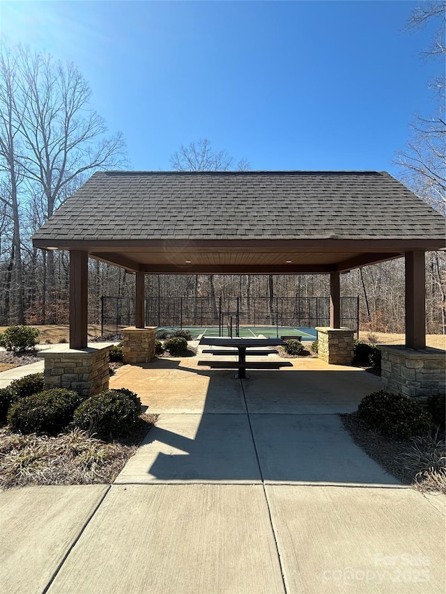 view of community with driveway, fence, a carport, and a gazebo