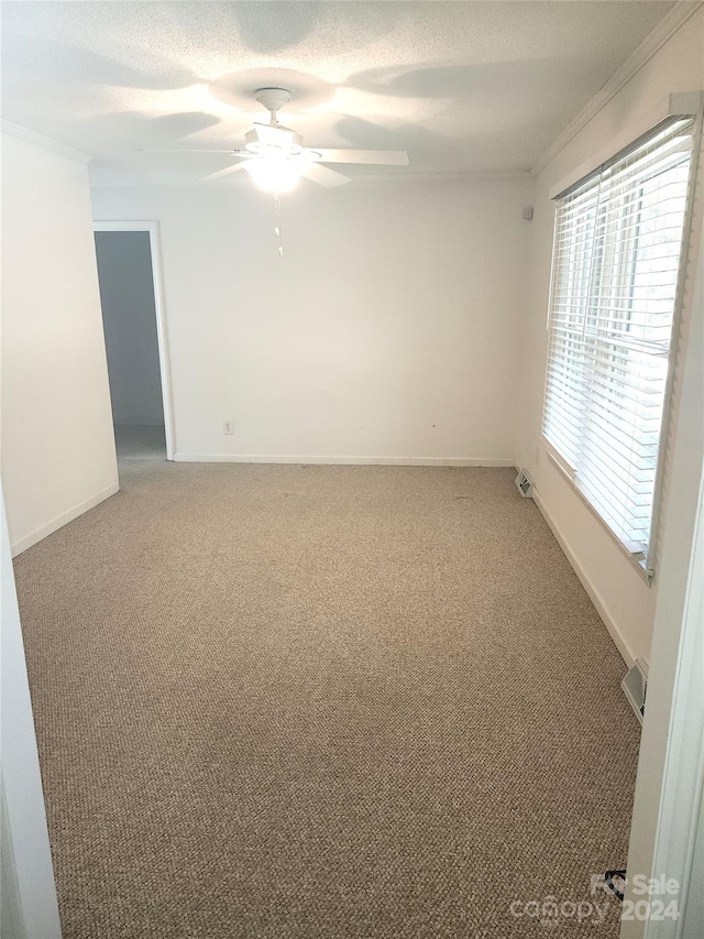 carpeted spare room featuring ornamental molding, a textured ceiling, and ceiling fan